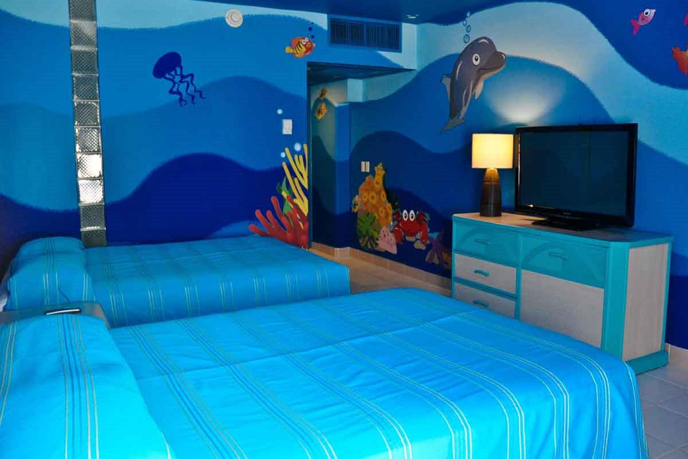 Grand Oasis Palm Ξενοδοχείο Κανκούν Εξωτερικό φωτογραφία The photo shows a brightly colored hotel room with a themed underwater design. The walls are painted in various shades of blue, resembling ocean water, and feature colorful sea creatures such as fish and a dolphin. There are two beds with blue stripe
